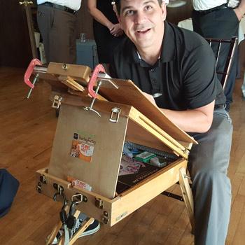 Dennis sitting at his easel drawing caricartures